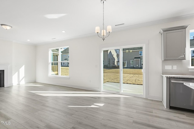 unfurnished dining area featuring a notable chandelier, light wood-type flooring, and crown molding