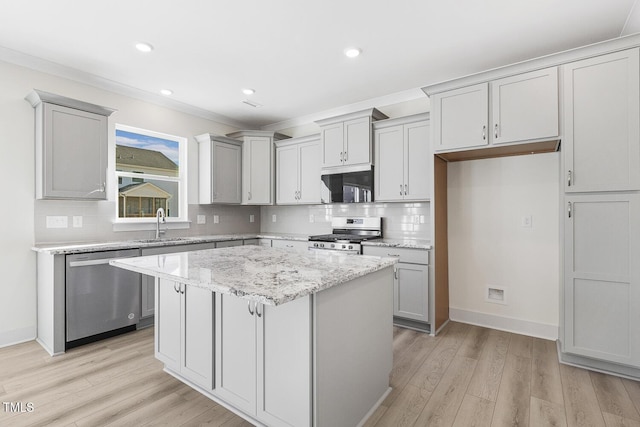 kitchen featuring appliances with stainless steel finishes, light hardwood / wood-style floors, light stone counters, a kitchen island, and sink