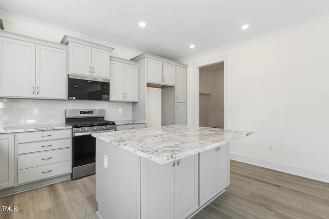 kitchen with stainless steel appliances, light stone countertops, light hardwood / wood-style floors, and a center island