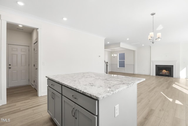 kitchen featuring a chandelier, a center island, decorative light fixtures, light wood-type flooring, and gray cabinets