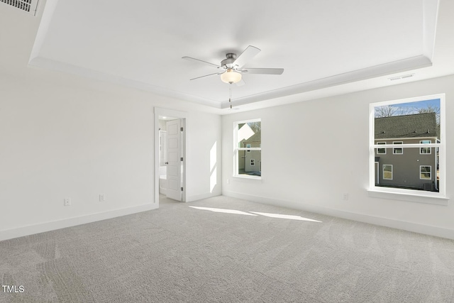 empty room featuring ceiling fan, a raised ceiling, and carpet