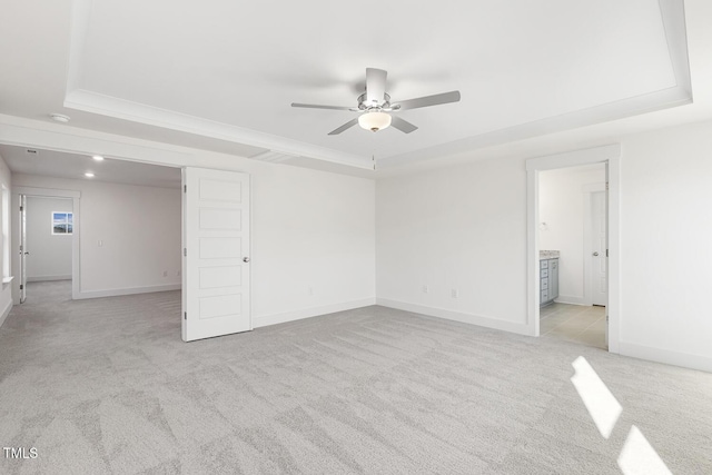 empty room featuring ceiling fan, light colored carpet, and a tray ceiling