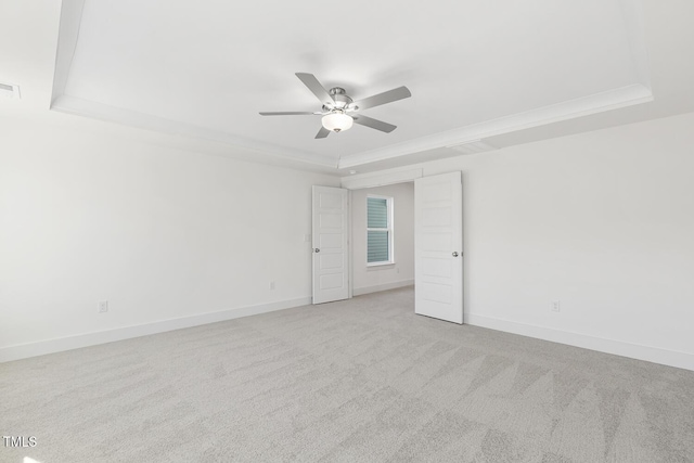 carpeted empty room featuring ceiling fan, a tray ceiling, and crown molding