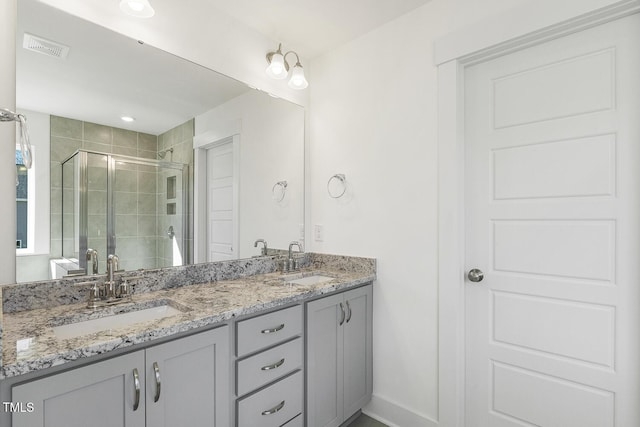 bathroom featuring a shower with door and vanity