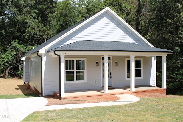 bungalow-style home featuring a porch, roof with shingles, and a front yard