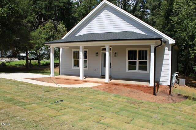 view of front of house featuring a front lawn, central air condition unit, and covered porch