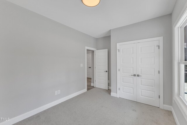 unfurnished bedroom featuring light carpet and a closet