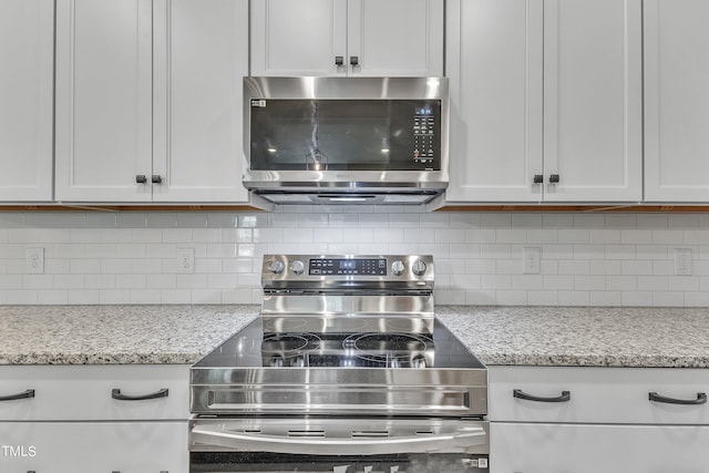 kitchen featuring appliances with stainless steel finishes, white cabinets, and decorative backsplash