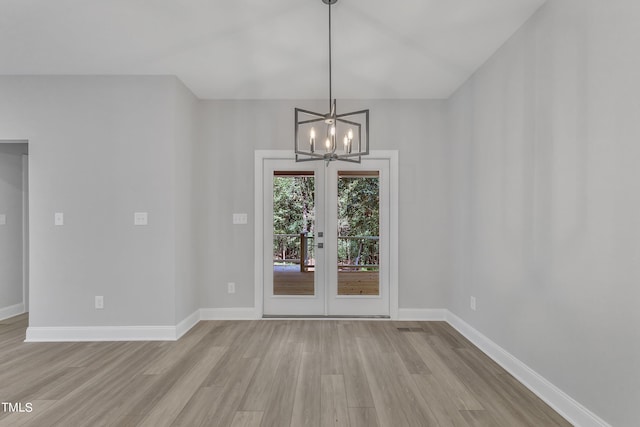 unfurnished dining area with french doors, a chandelier, and light hardwood / wood-style flooring