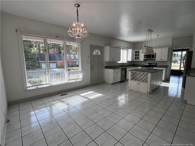 kitchen with appliances with stainless steel finishes, white cabinetry, a center island, and pendant lighting