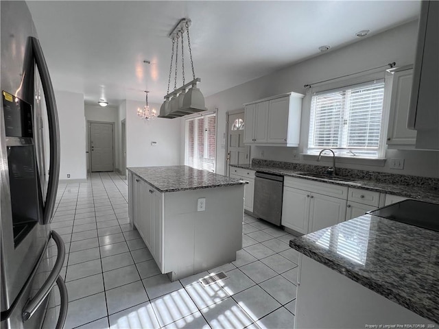 kitchen featuring appliances with stainless steel finishes, sink, a center island, white cabinetry, and pendant lighting