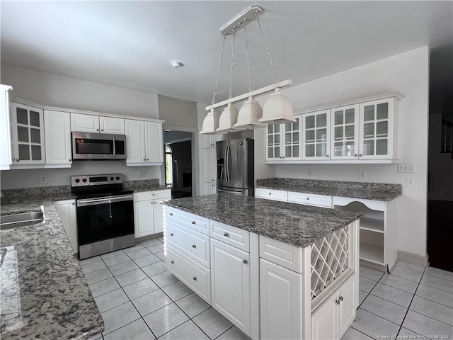 kitchen with appliances with stainless steel finishes, a center island, pendant lighting, white cabinets, and light tile patterned floors