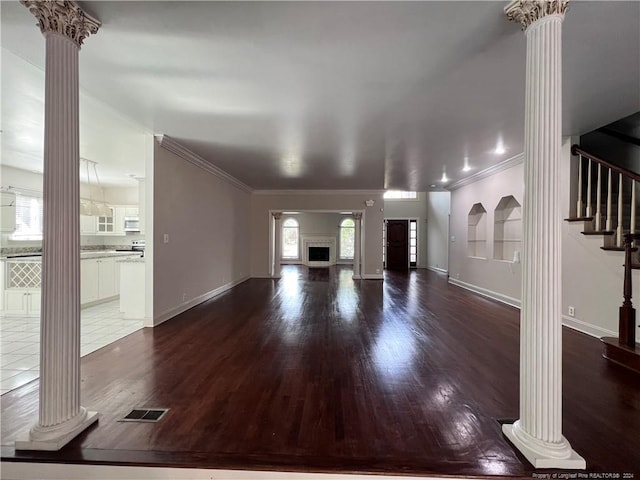 unfurnished living room with dark wood-type flooring, ornate columns, and a healthy amount of sunlight