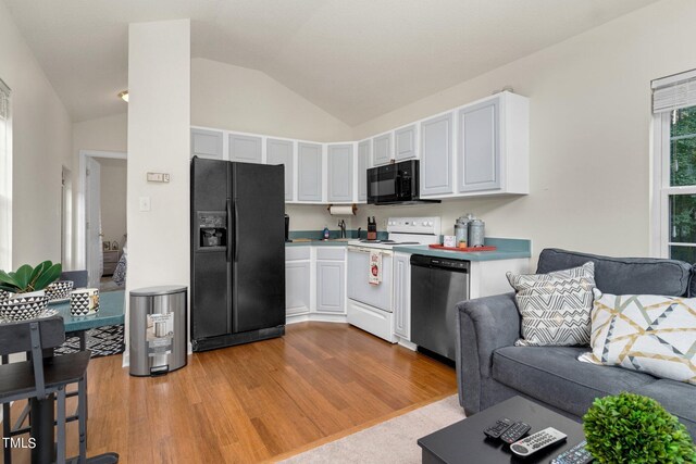 kitchen featuring black appliances, white cabinetry, vaulted ceiling, and light hardwood / wood-style flooring