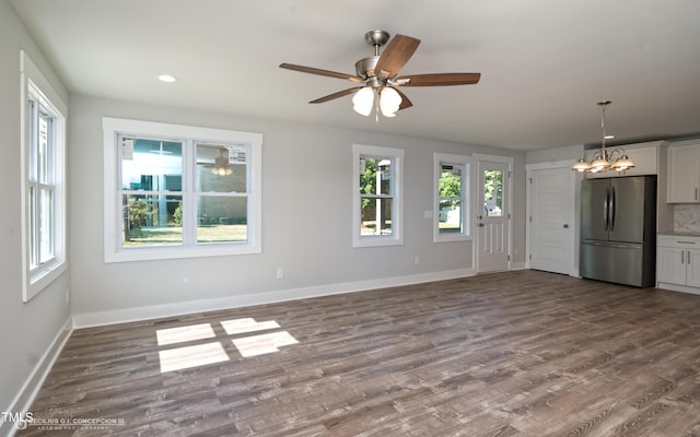 unfurnished living room with wood-type flooring and ceiling fan with notable chandelier