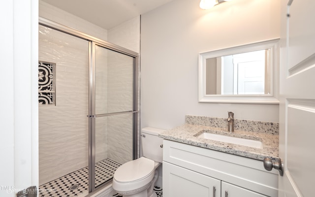 bathroom featuring a shower with door, vanity, and toilet