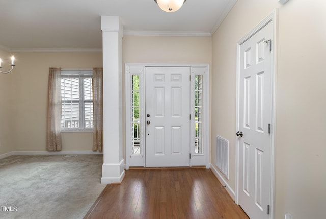 entryway featuring hardwood / wood-style flooring, ornamental molding, and decorative columns