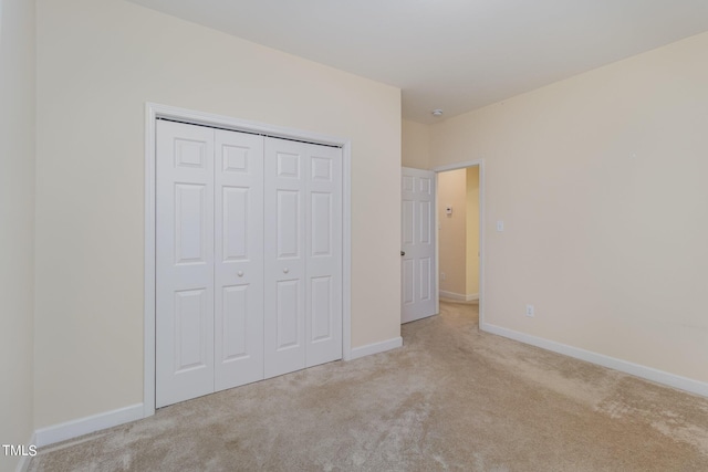 unfurnished bedroom with light colored carpet and a closet