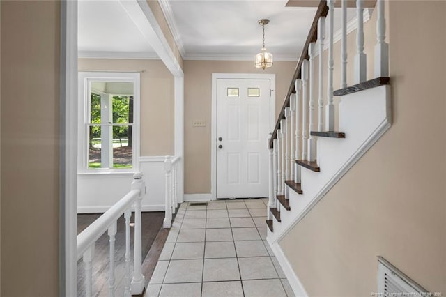 foyer with ornamental molding, light tile patterned floors, and an inviting chandelier