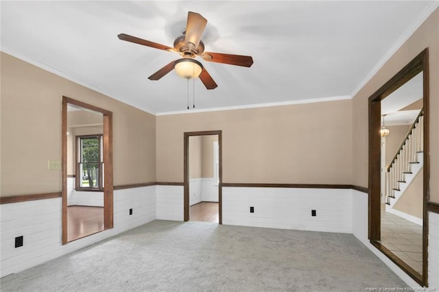 carpeted spare room with ceiling fan and ornamental molding