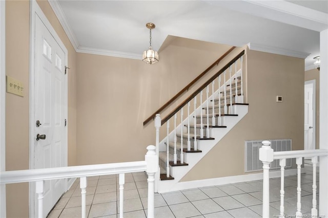 foyer with light tile patterned floors and crown molding