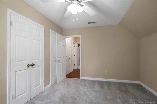 unfurnished bedroom with multiple closets, ceiling fan, light carpet, and lofted ceiling