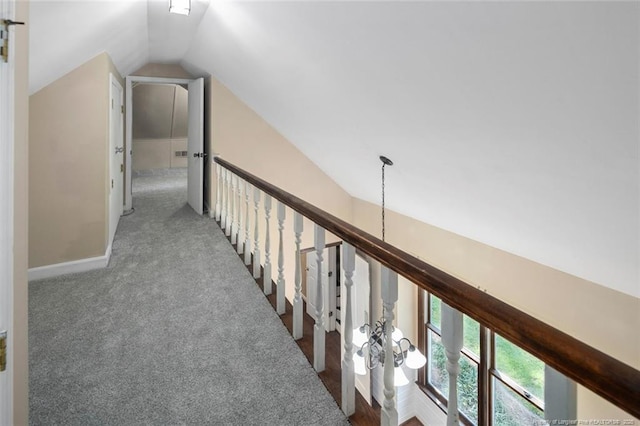 hallway with carpet floors and vaulted ceiling