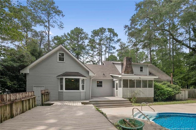 rear view of property with a sunroom and a pool side deck