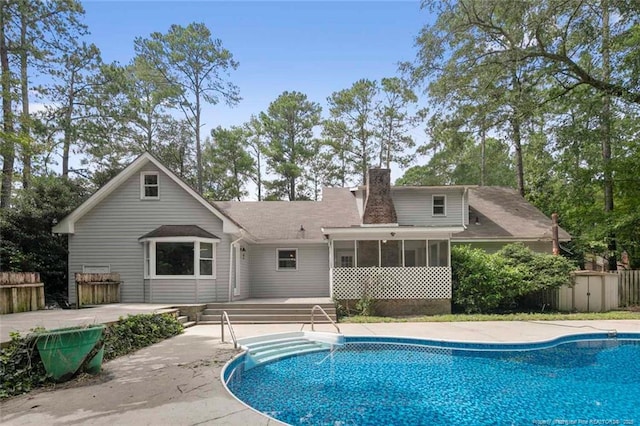 back of property featuring a sunroom, a patio, and a storage unit