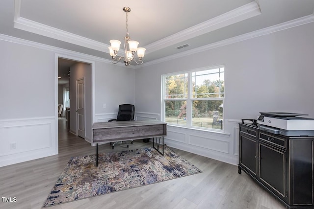 office space with crown molding, a notable chandelier, a tray ceiling, and light hardwood / wood-style floors