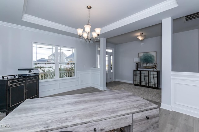 unfurnished dining area featuring an inviting chandelier, ornamental molding, a tray ceiling, and hardwood / wood-style floors