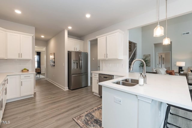 kitchen featuring sink, stainless steel appliances, hanging light fixtures, and white cabinets