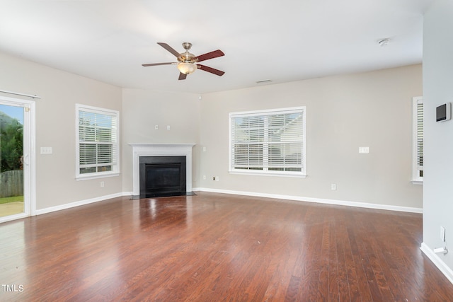 unfurnished living room featuring dark wood-type flooring and ceiling fan