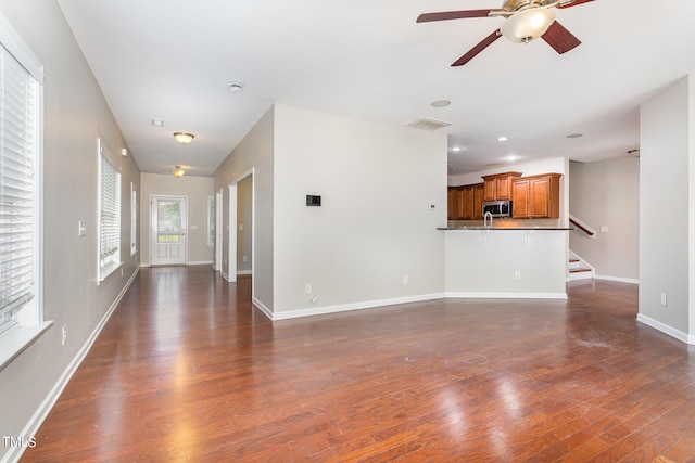 unfurnished living room featuring ceiling fan and dark hardwood / wood-style floors