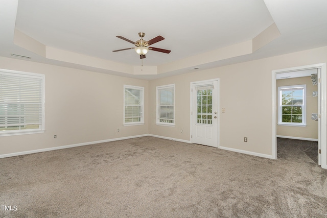 carpeted spare room featuring a raised ceiling and ceiling fan