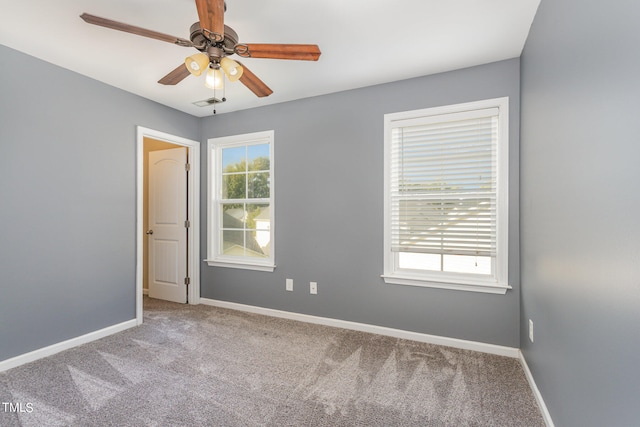 empty room featuring a wealth of natural light, ceiling fan, and light carpet