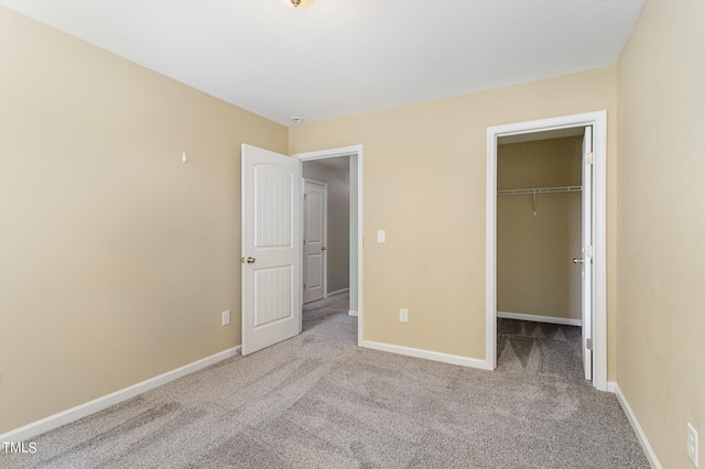 unfurnished bedroom with a closet, a spacious closet, and light carpet