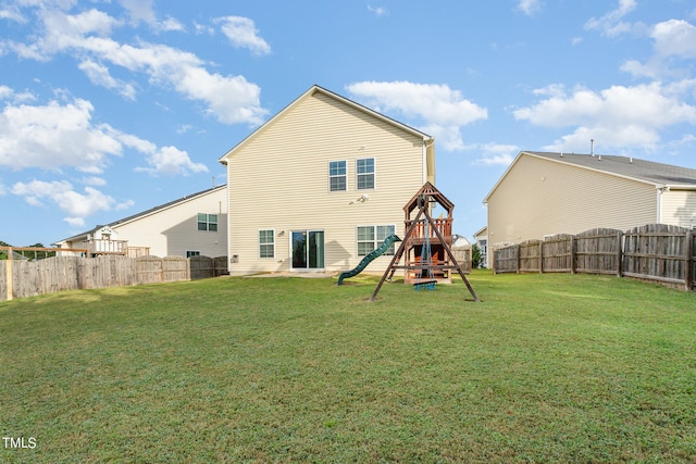 back of house featuring a lawn and a playground