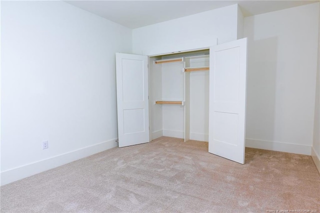 unfurnished bedroom featuring light colored carpet and a closet