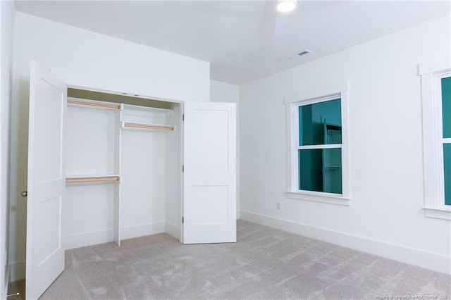 unfurnished bedroom featuring a closet and light colored carpet