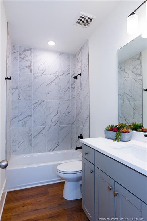 full bathroom featuring vanity, toilet, wood-type flooring, and tiled shower / bath