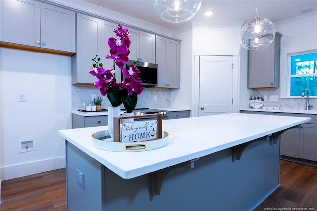 kitchen featuring tasteful backsplash, a center island, hanging light fixtures, and ornamental molding