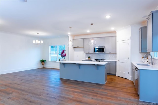 kitchen featuring appliances with stainless steel finishes, tasteful backsplash, sink, decorative light fixtures, and a center island