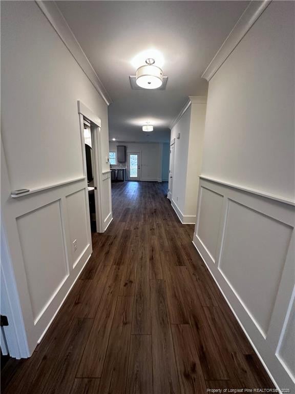 corridor with ornamental molding and dark wood-type flooring