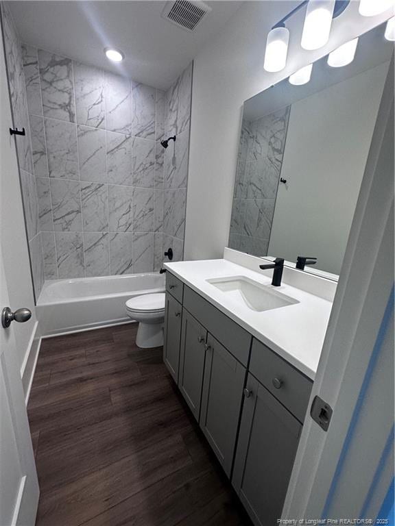 full bathroom featuring hardwood / wood-style flooring, vanity, toilet, and tiled shower / bath combo