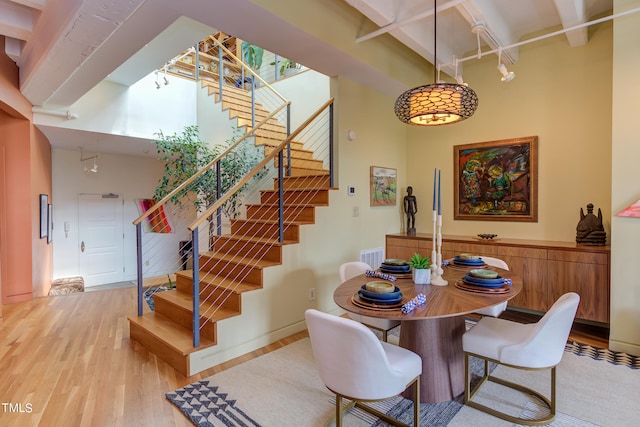 dining room with light wood-type flooring and a towering ceiling