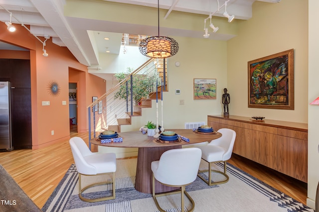 dining space with beamed ceiling and light hardwood / wood-style floors