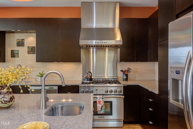 kitchen with appliances with stainless steel finishes, dark brown cabinets, light stone countertops, wall chimney exhaust hood, and tasteful backsplash