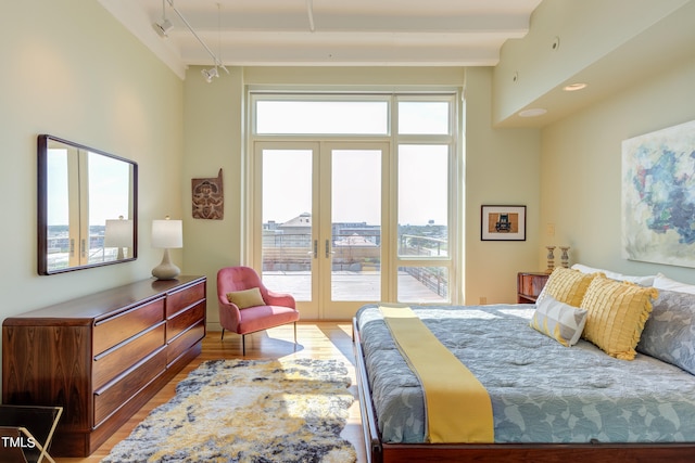 bedroom featuring wood-type flooring, french doors, multiple windows, and rail lighting