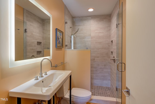 bathroom with toilet, sink, and a shower with shower door